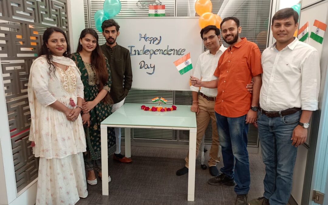 ProCARE members gathering to celebrate India's Independence Day. There are six people in this image, standing in a room with a white board that says Happy Independence Day on it. Some are holding Indian flags.